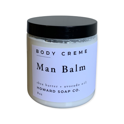 Product image of the Man Balm lotion. Clear jar with white lotion and black lid.