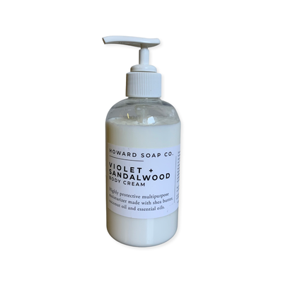 Product image of the Violet + Sandalwood Body Cream. Clear bottle, white lotion, with white pump.